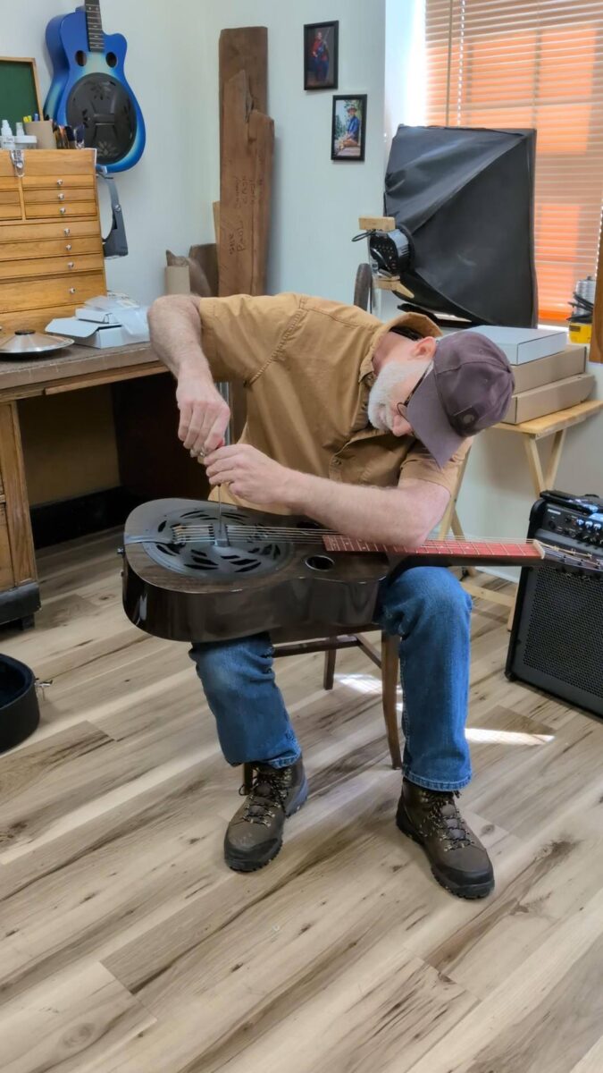 Paul Beard making adjustments to a resophonic guitar